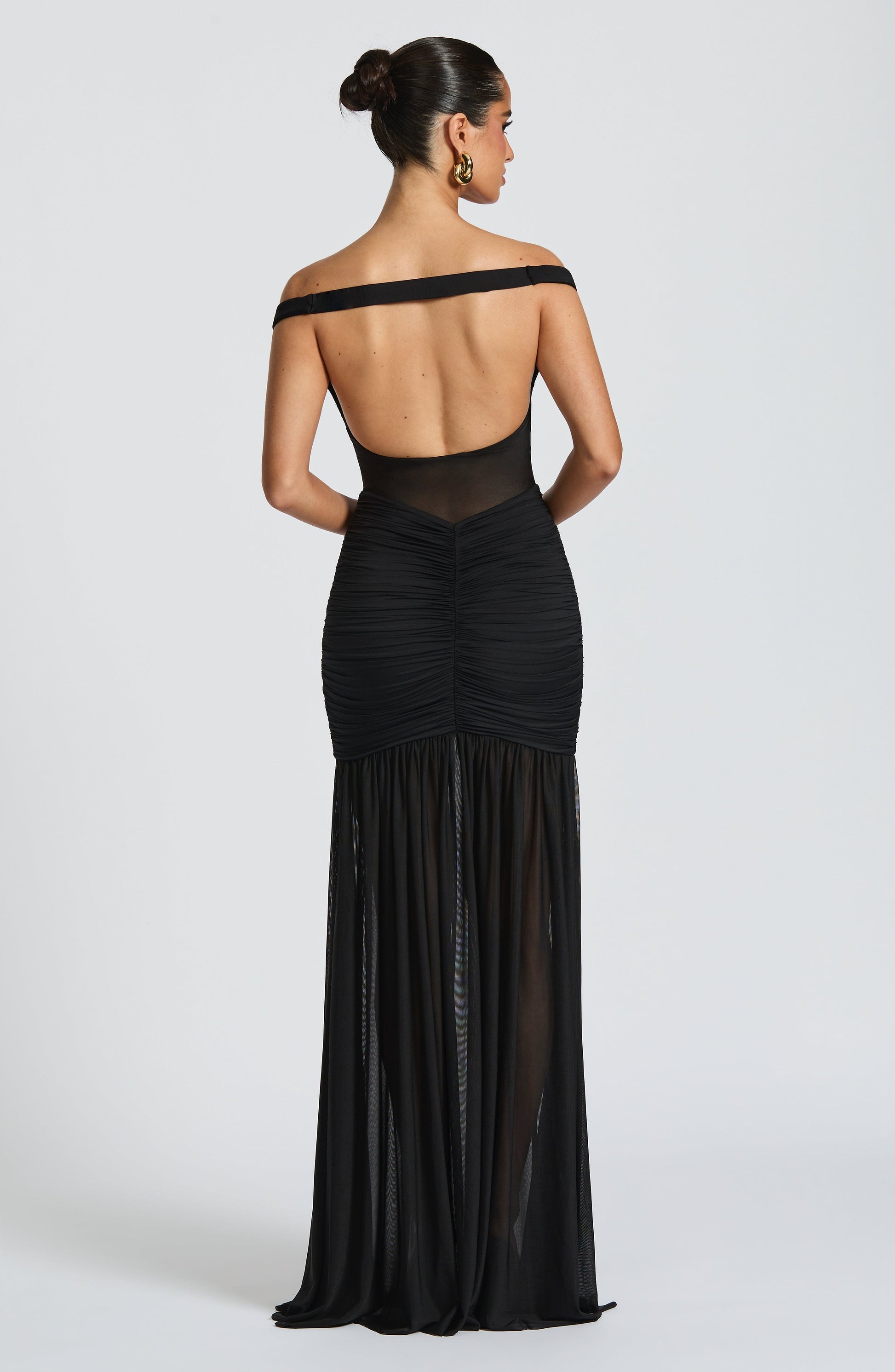 Black off-shoulder evening gown with sheer details on a white background