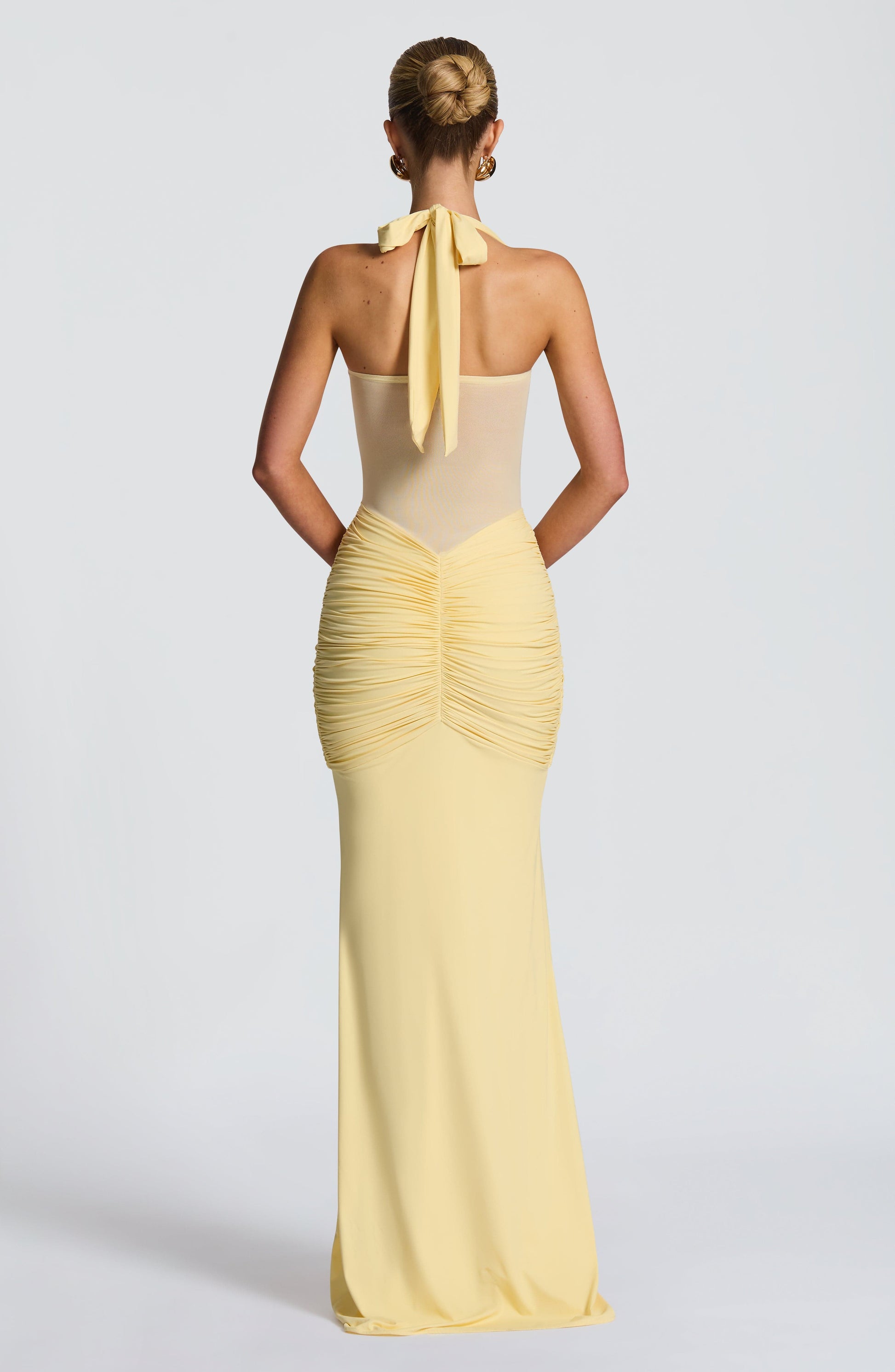 Woman wearing a yellow evening gown with a plain background