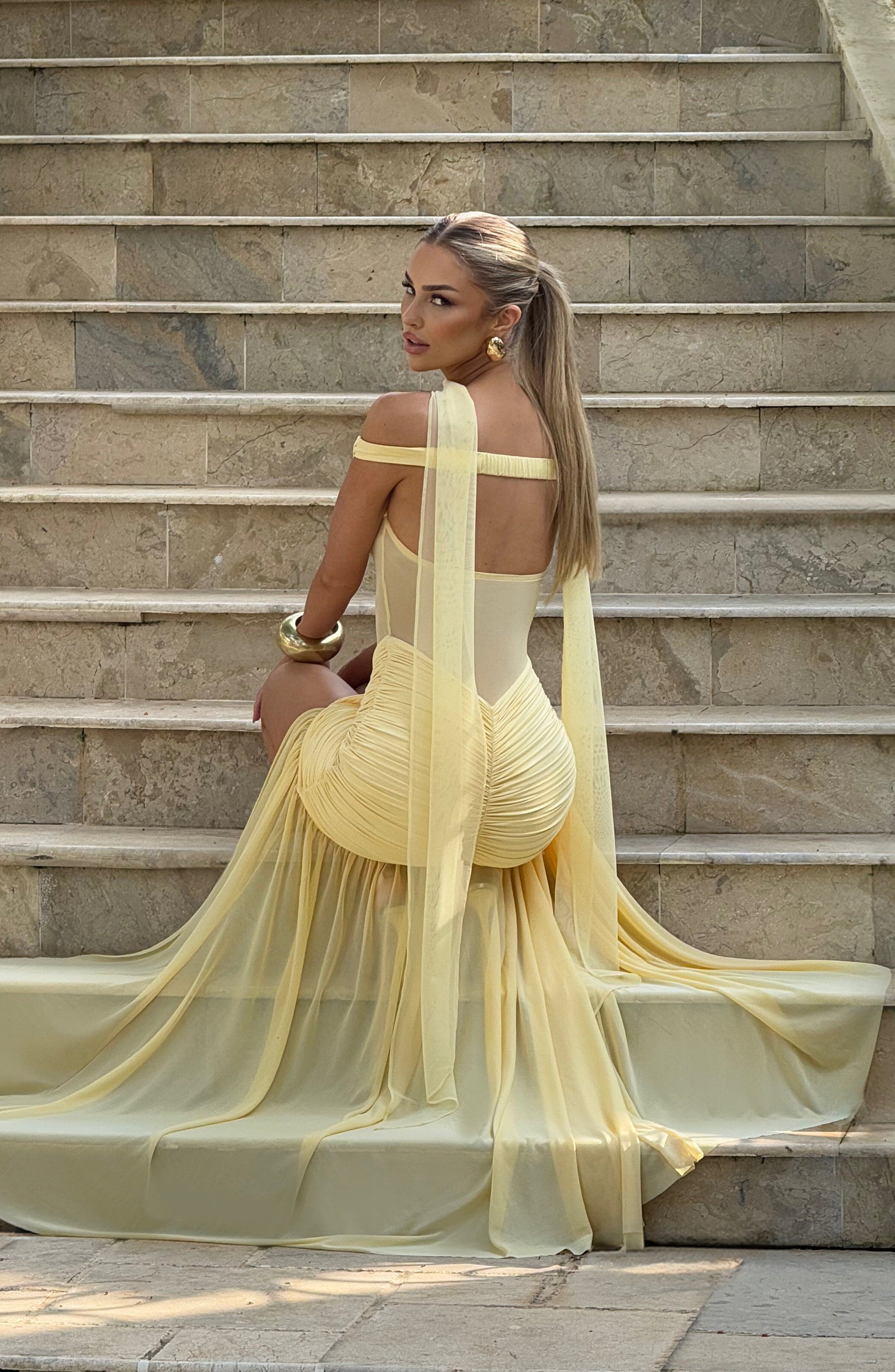 Woman in a yellow dress sitting on stone steps