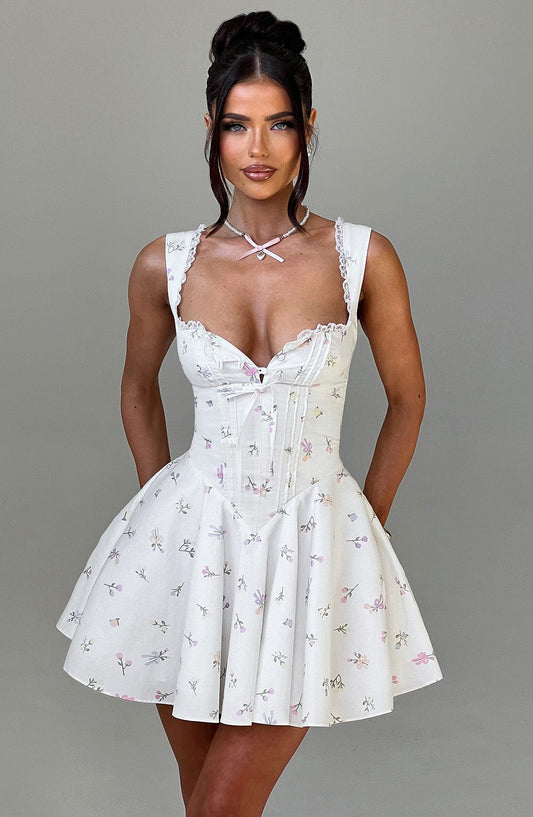 Woman wearing a white floral dress against a gray background