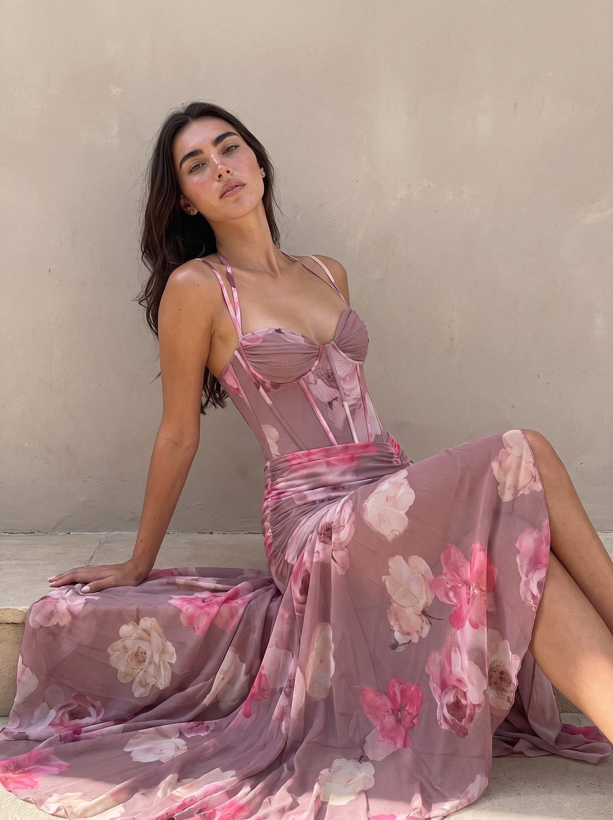 Woman seated on a stone step in a blurred floral corset gown, the sheer chiffon skirt pooling around her — SÉRAPHINE CORSET GOWN — Kalii