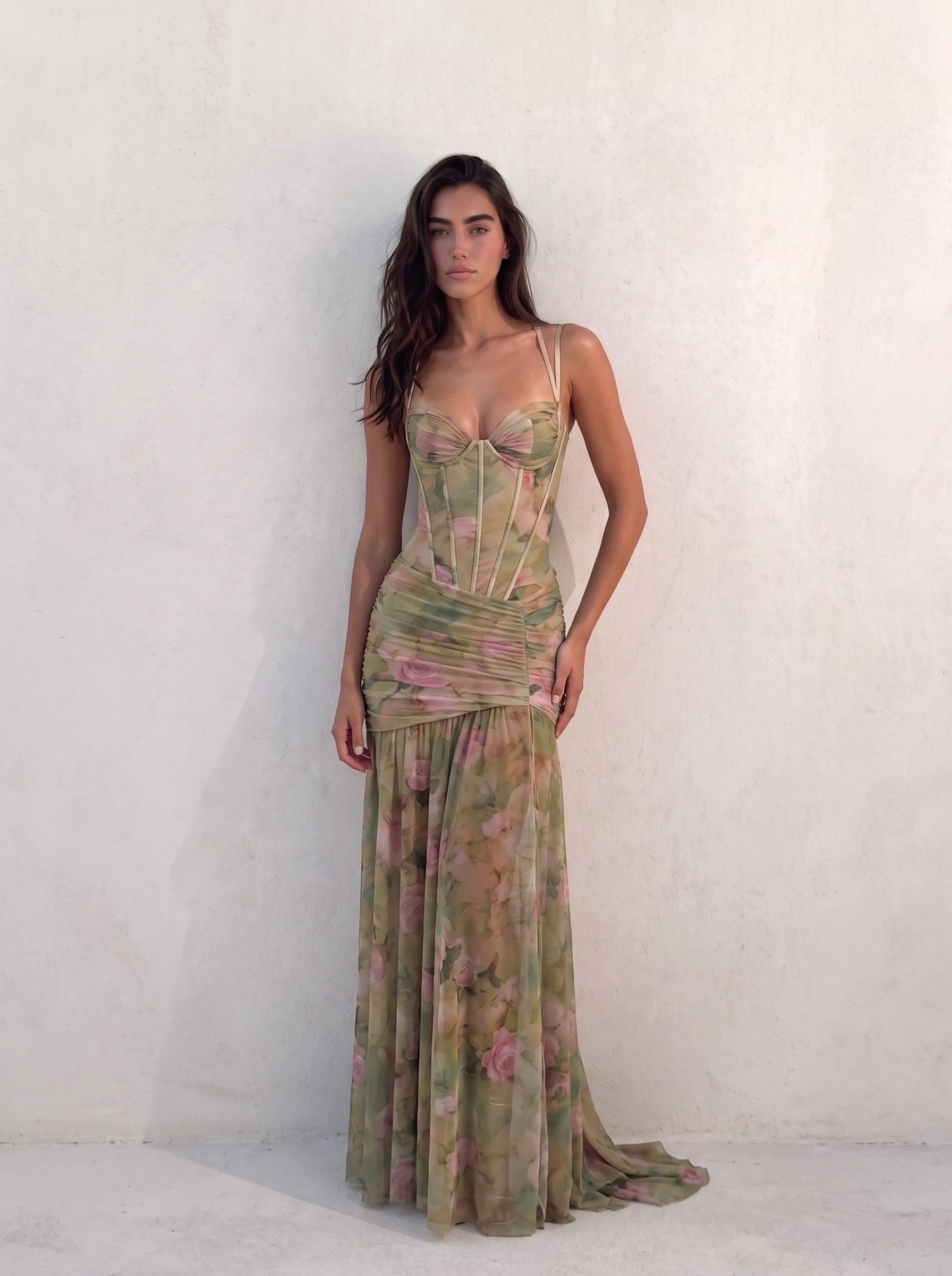Woman wearing a sage green watercolour floral corset gown with a boned bodice, against a sunlit plaster wall — SÉRAPHINE CORSET GOWN — Kalii