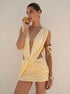 Woman wearing a lemon yellow toga drape mini dress with deep V neckline and open sides — SOLÈNE DRAPE MINI DRESS — Kalii