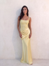 VESPERA BEADED GOWN in lemon — leaning against a sun-washed plaster wall — Kalii